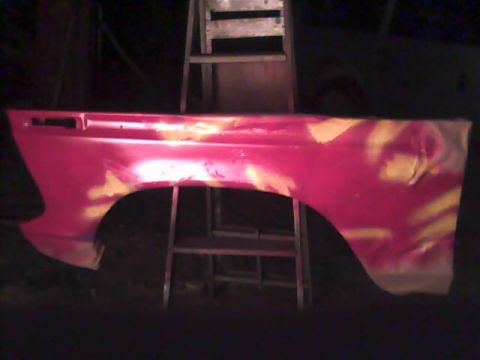 1978 Ford Bronco - A single vehicle fender, painted red with yellow markings, is shown against a dark background.