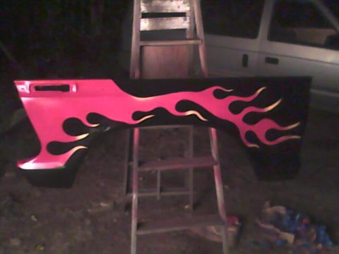 1978 Ford Bronco - A car fender with flame decals is displayed on a ladder, with a vehicle visible in the background.