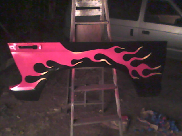 Red and black flame-decaled car fender on a ladder