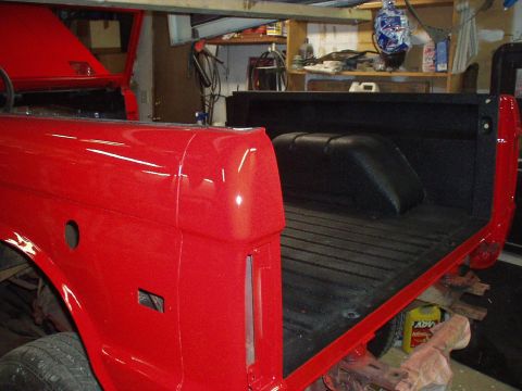 1973 Ford Bronco - The rear section of a red 1973 Ford Bronco, showing the bed and fender, is visible in a garage setting.