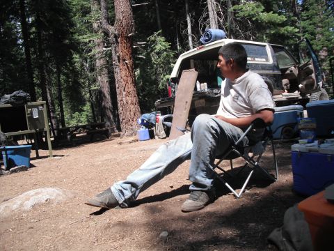 1991 Ford Bronco - Man relaxes at a campsite next to a 1991 Ford Bronco.