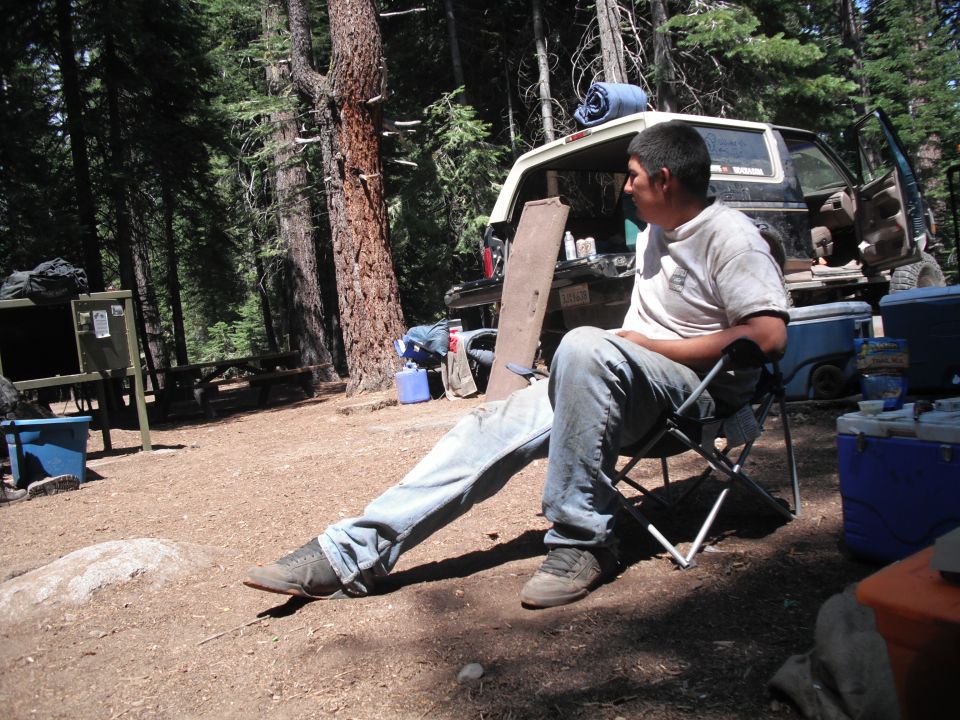 1991 Ford Bronco parked at a campsite with a man sitting in a chair