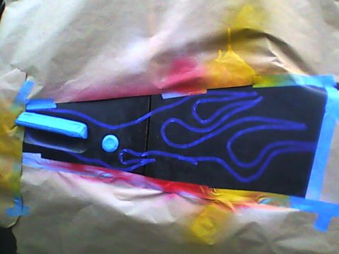 1978 Ford Bronco - A black body panel taped off with blue masking tape and paper, with a flame design laid out in blue fine-line tape ready for spraying. Over…