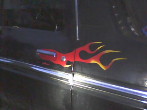 1978 Ford Bronco - Close-up of red-to-yellow flame graphics applied to the door of a black vehicle, wrapping around the chrome door handle.