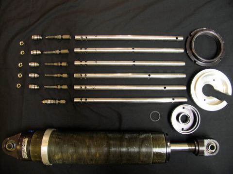 1984 Ford Bronco - Various parts of a shock absorber are laid out for inspection, including the main body and internal components.