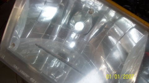2004 Ford Crown Victoria - A close-up view of a vehicle's headlight assembly, showing the textured lens and internal components.