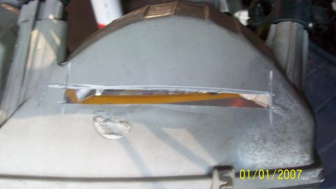 2004 Ford Crown Victoria - Close-up of a modified headlight assembly, showing internal wiring and a yellow reflector behind a cut-out section.