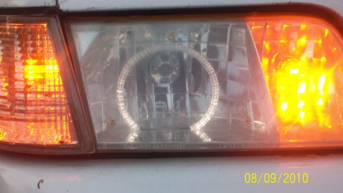 2004 Ford Crown Victoria - The front passenger side headlight and amber turn signal are visible, with a halo light ring inside the main headlight housing.