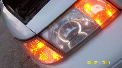 2004 Ford Crown Victoria - Close-up of a white car's rear tail light assembly, showing the illuminated amber turn signal and clear housing.