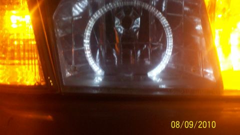 2004 Ford Crown Victoria - Close-up of a 2004 Ford Crown Victoria headlight assembly, showing the halo ring and amber turn signal.