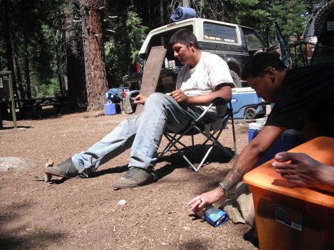 1991 Ford Bronco - A 1991 Ford Bronco is parked at a campsite while two people relax and another reaches for a snack.