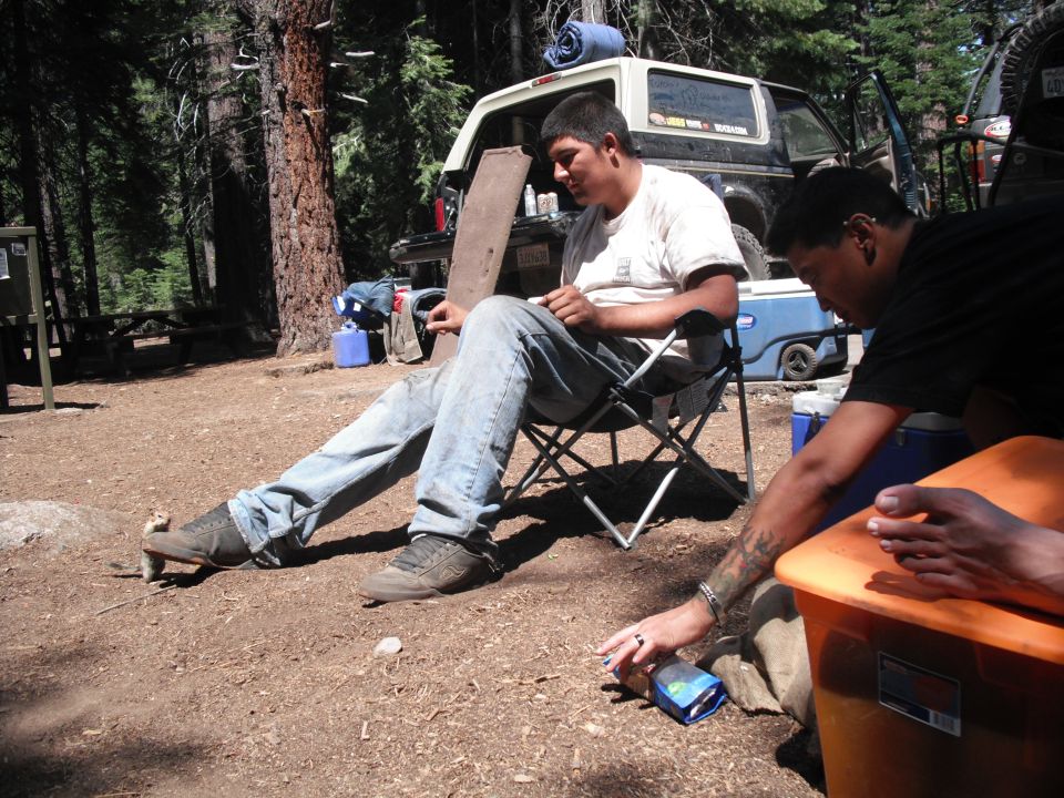 1991 Ford Bronco parked at campsite with people sitting nearby