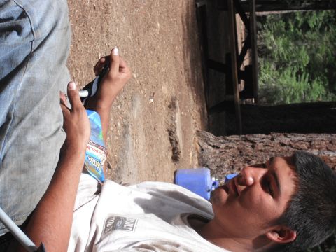 1991 Ford Bronco - A person rests outdoors, holding a bottle of water. The scene appears to be in a wooded area with a wooden structure in the background.