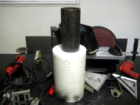 1996 Ford Bronco - A metal pipe sits atop a stack of white discs, surrounded by various tools on a workbench.
