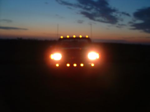 1988 Ford F-150 - Front view of a truck with its lights on against a twilight sky.