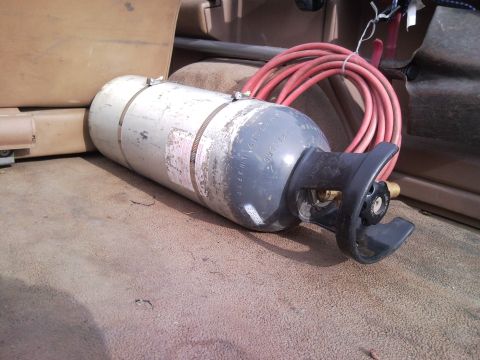 1989 Ford Bronco - A cylinder and red hose are visible in the cargo area of a vehicle.