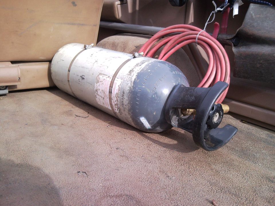 Cylinder with red hose inside a vehicle's cargo area