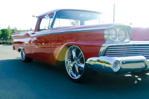1959 Ford Ranchero - A red pickup truck is shown from a low angle, highlighting its chrome wheels and custom front end.