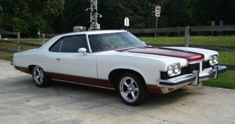 1976 Ford Ranchero - This two-tone coupe features a maroon stripe on the hood and a matching maroon lower body accent.