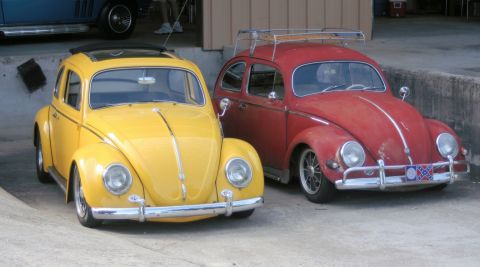 1976 Ford Ranchero - Two classic Volkswagen Beetles, one yellow with a sunroof and one red with a roof rack, are parked outdoors.