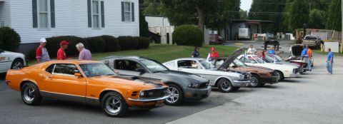 1976 Ford Ranchero - Multiple Ford Mustangs lined up, with the orange model from 1970 in the front.