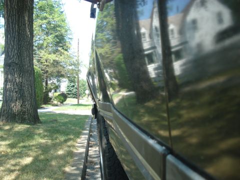 1988 Ford Bronco - Side view of a dark 1988 Ford Bronco, showing its body panel and chrome trim.
