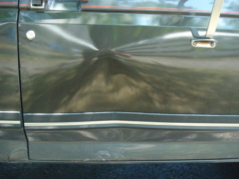 1988 Ford Bronco - Close-up of a 1988 Ford Bronco door showing damage and rust.
