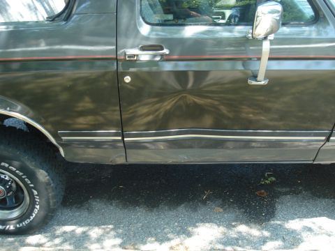 1988 Ford Bronco - This SUV's side panel shows significant damage and a decorative stripe.