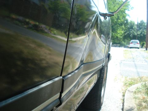 1988 Ford Bronco - Side view of a black SUV with significant damage to the body panel.
