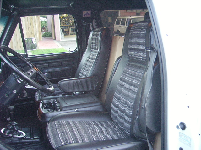 1978 Ford Bronco interior showing front seats, steering wheel, and center console. Another SUV is visible through the window