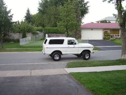 1978 Ford Bronco - A white 1978 Ford Bronco is shown from the side on a residential street with a house and garage in the background.