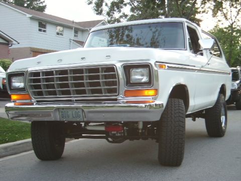1978 Ford Bronco - A white 1978 Ford Bronco is parked on a street, with another vehicle visible behind it.