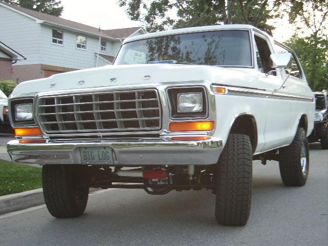 White 1978 Ford Bronco with a chrome grille and a "BIG LOG" license plate, viewed from the front
