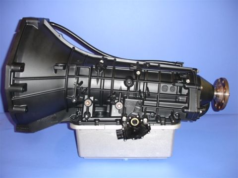 1990 Ford Bronco - A rebuilt Ford automatic transmission photographed on a plain blue studio backdrop, shown from the side with the bellhousing at left and th…