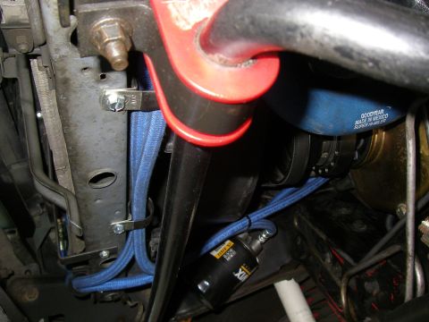 1990 Ford Bronco - Under-hood close-up of blue braided transmission cooler lines routed along the frame rail and secured with new zinc-plated clamps, running…