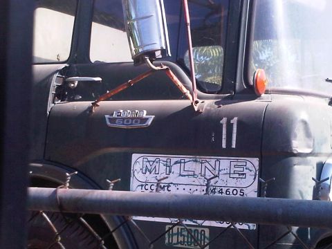 1986 Ford Bronco - A dark green Ford 600 truck is seen from the side, a Milne logo and the number 11 on its door.