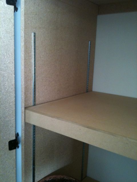 1966 Ford Bronco - Interior view of a storage shelving unit with particle board shelves and metal supports.