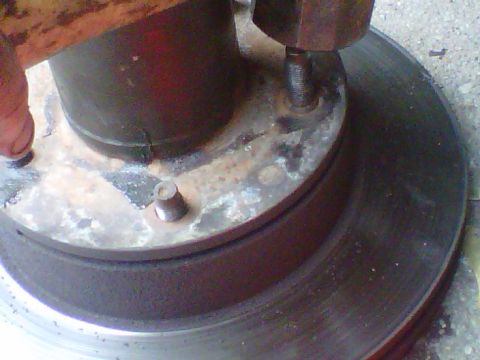 1995 Ford Bronco - Tight close-up of a wheel hub and brake rotor on the ground while a rusty sledge hammer head drives a wheel stud out from the back, the thr…