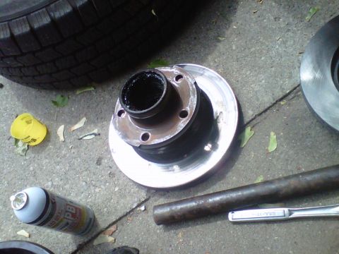 1995 Ford Bronco - Parts for a vehicle brake job are laid out on the ground, including a hub assembly and rotors.