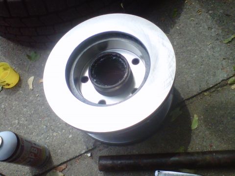 1995 Ford Bronco - A new brake rotor sits on the ground next to a tire and a can of spray.