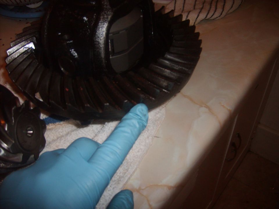 Differential gear set with a gloved hand pointing to teeth