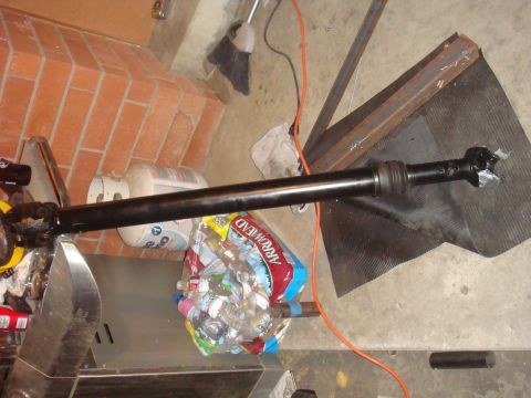 1992 Ford Bronco - A driveshaft is shown with a bag of water bottles and a propane tank in the background.