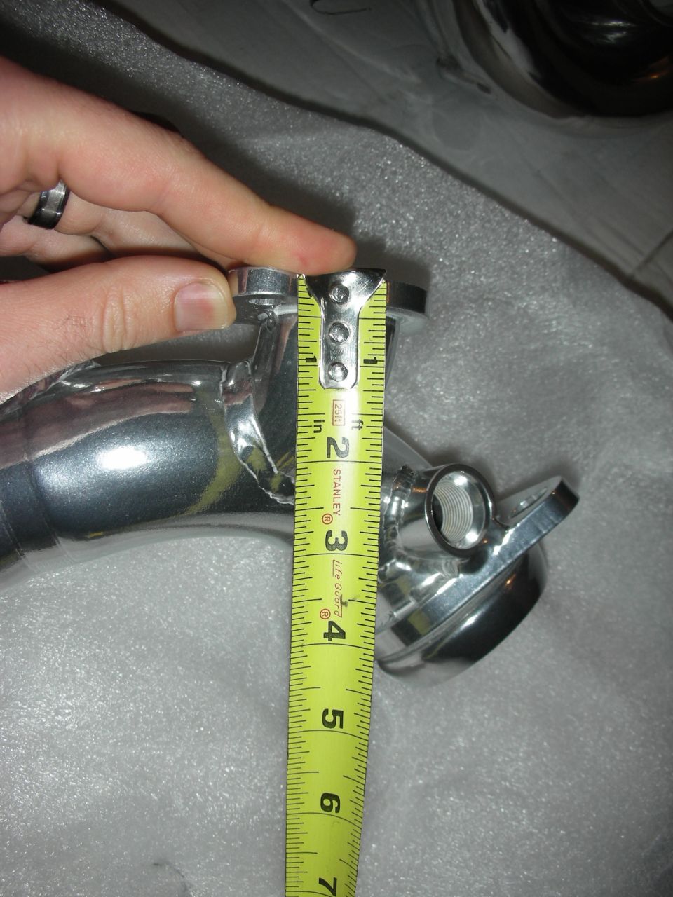 Chrome exhaust pipe being measured with a Stanley tape measure
