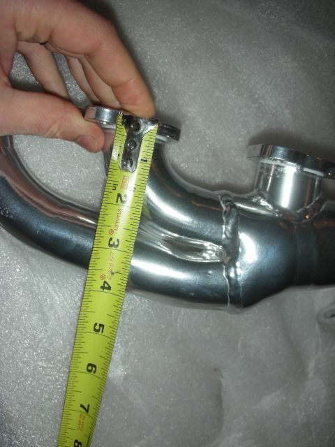 1998 Ford Crown Victoria - A tape measure is used to measure a chrome exhaust pipe, likely for aftermarket parts.