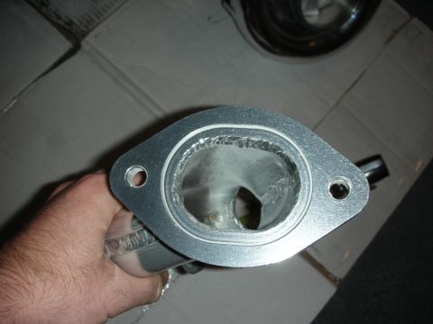 1998 Ford Crown Victoria - Close-up of a metal exhaust manifold flange, showing the internal welds and connection points.