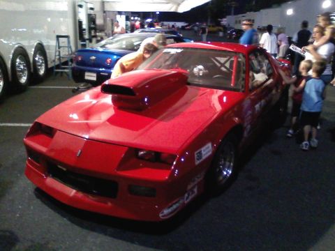 1989 Chevrolet Camaro - Red 1989 Chevrolet Camaro drag car with a prominent hood scoop and racing stickers is parked outdoors.
