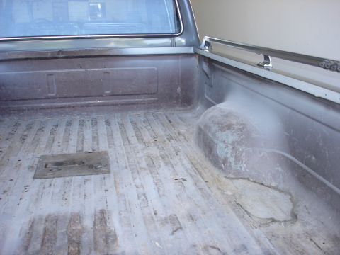 1979 Ford F-250 - The interior of a truck bed, showing the bedliner and a chrome rail along the top edge.
