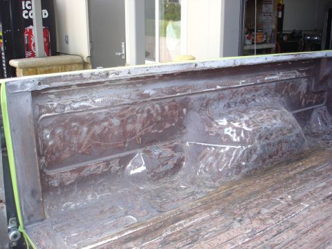 1979 Ford F-250 - The interior of a truck bed, stripped down to bare metal, reveals signs of repair and preparation for refinishing.