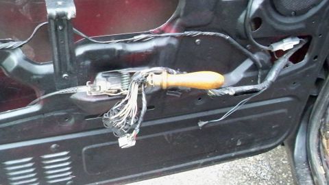 1994 Ford Bronco - Close-up of a vehicle's door panel interior, showing exposed wiring harness and a tool.