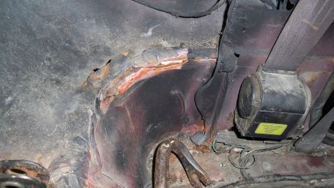 1994 Ford Bronco - Significant rust damage is visible on the vehicle's frame, along with a seatbelt retractor.